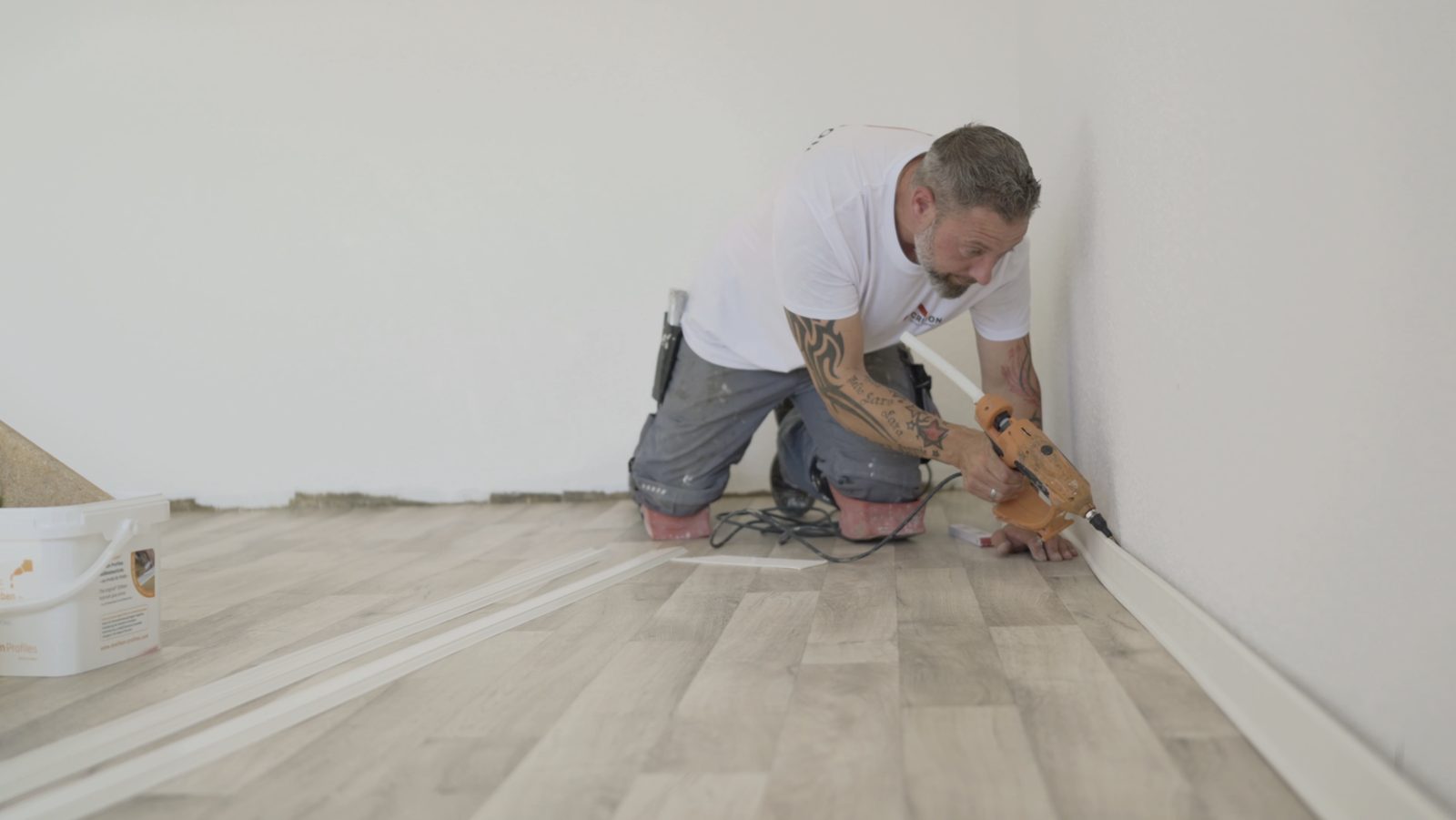 Bodenleger beim Verlegen mit Sockelleisten